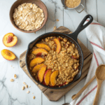 Peach crisp in a cast-iron skillet with golden oat topping